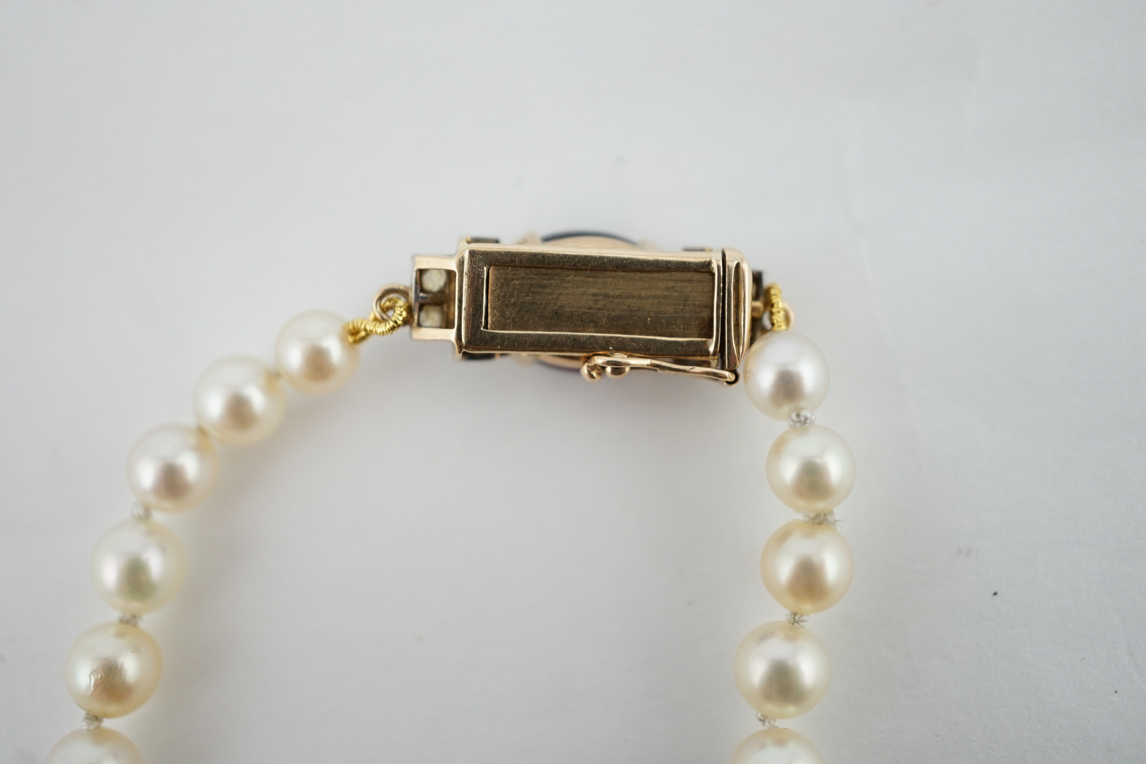 A single strand graduated cultured pearl necklace, with a gold, garnet and rose cut diamond cluster set clasp